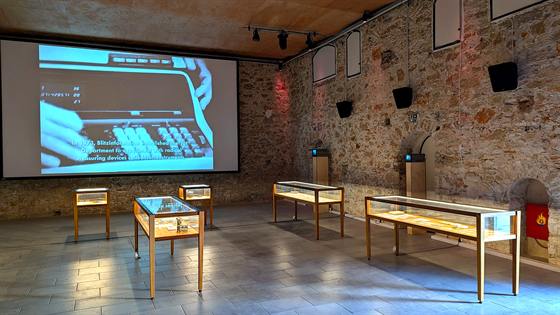 Gallery installation view with a projection and vitrines